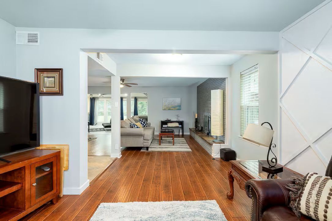 A living room with a TV, wooden flooring, a sofa, a coffee table, and a fireplace.