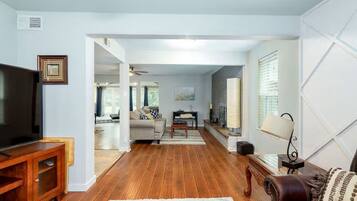 A living room with a TV, wooden flooring, a sofa, a coffee table, and a fireplace.