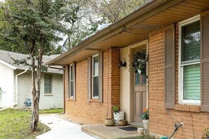 A brick house with a front porch, a mailbox, and a tree in the yard. - Moody Moon Cottage 3bd with Pool Table 10min dfw (Irving)