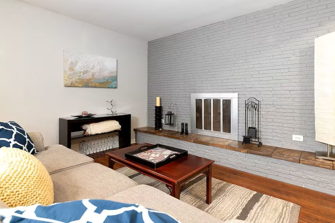 A living room with a sofa, coffee table, fireplace, and a stone wall.