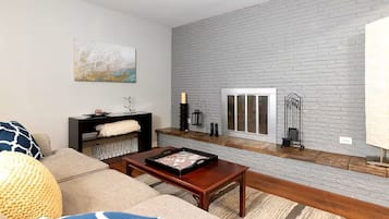 A living room with a sofa, coffee table, fireplace, and a stone wall.