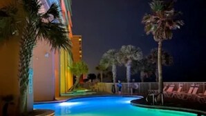 A swimming pool with a curved edge, surrounded by palm trees and lounge chairs. - New Listing Discount! 1804 W Splash Beach Resort-1BR+Bunks-Gulf Views (Panama City Beach)