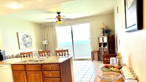 A kitchen with a large island, wooden cabinets, and a dining area with a table and chairs. - New Listing Discount! 1804 W Splash Beach Resort-1BR+Bunks-Gulf Views (Panama City Beach)