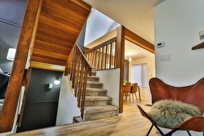 Eine Treppe mit Holzwangen, ein Essbereich mit Stühlen und ein gemütlicher Sessel.
