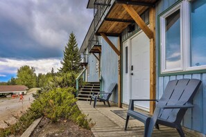 Ein Gebäude mit einer Holzterrasse, zwei Adirondack-Stühlen und einer Garagentür.