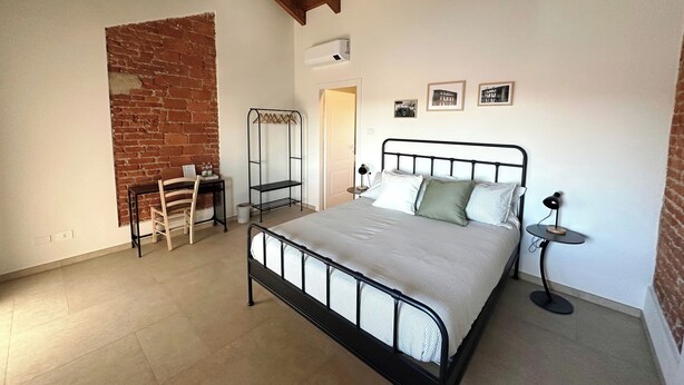 Quarto com cama, escrivaninha, cadeira, prateleira suspensa e porta.