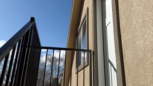 Portaat, jotka johtavat parvekkeelle, jossa on metallikaide, ikkuna ja seinään kiinnitetty valaisin.