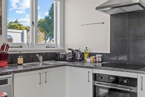 Moderni keittiö, jossa on ikkuna, leivänpaahdin, vedenkeitin ja liesituuletin.