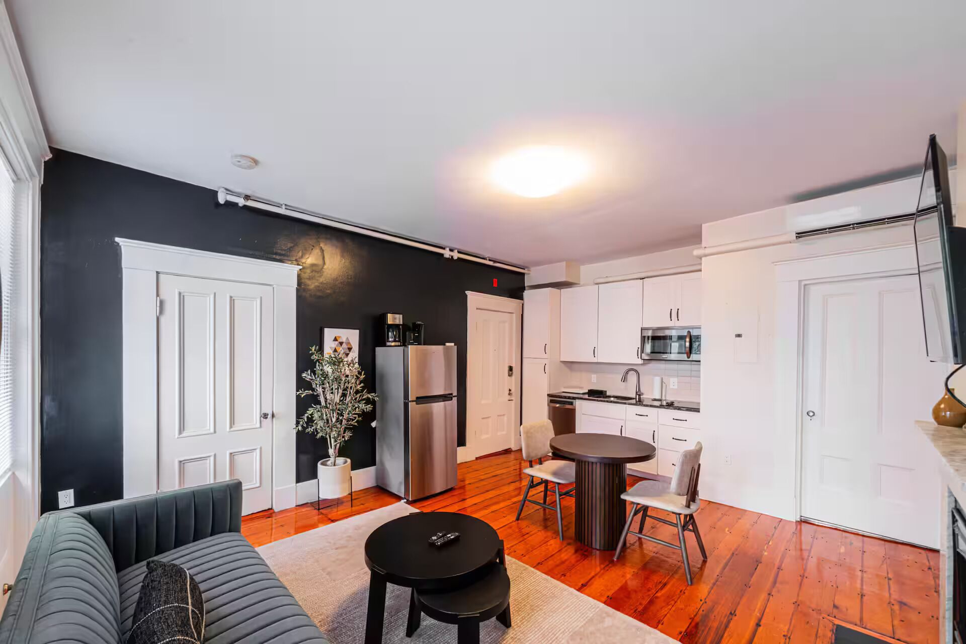 Ett kompakt bostadsutrymme med ett litet kök, en matplats och en sittgrupp.