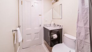 Een badkamer met een wit toilet, een wastafel met spiegel erboven, een handdoekrek en een douchegordijn.
