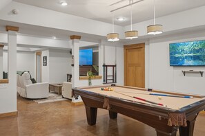 Une table de billard avec des billes, un canapé, un téléviseur et une porte en bois.