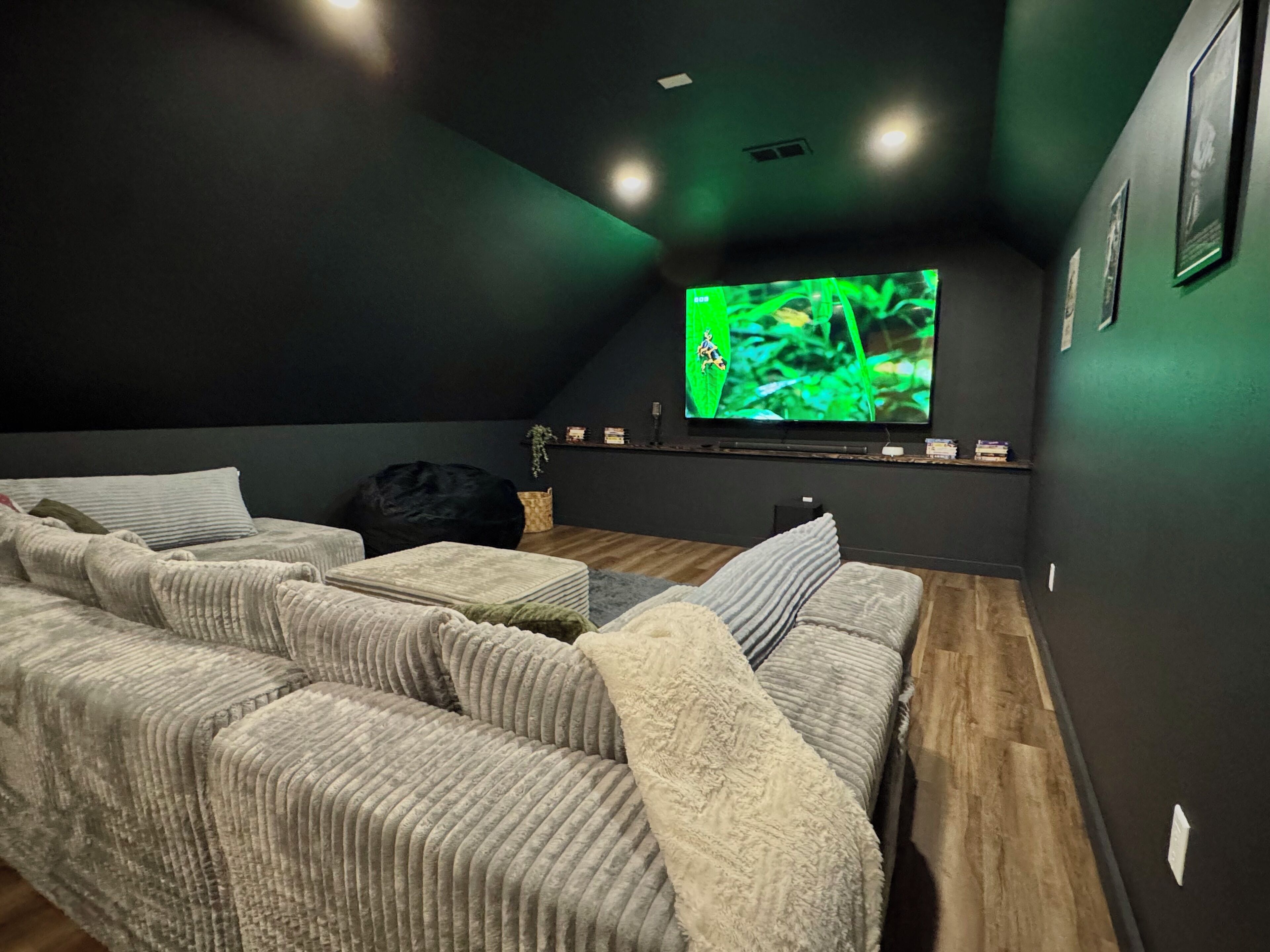Een gezellige kamer met een hoekbank, een flatscreen televisie en een donker plafond.
