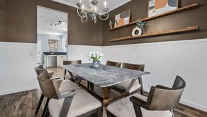 A dining area with a marble table, chairs, a chandelier, and decorative shelves. - New Centrally Located North Richland Hills Home (North Richland Hills)