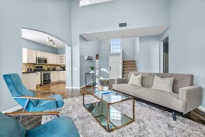 Una sala de estar amplia con un sofá, sillones y una mesa de centro de vidrio.