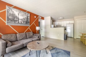 Ein modernes Wohnzimmer mit einer Couch, einem Couchtisch und einer Küche im Hintergrund.