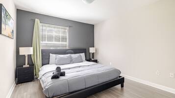 Een moderne slaapkamer met een bed, nachtkastjes en een raam met zonwering.