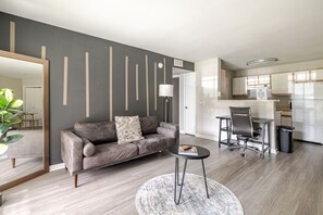 Ein modernes Wohnzimmer mit einem grauen Sofa, einem runden Couchtisch und einem gemusterten Teppich.