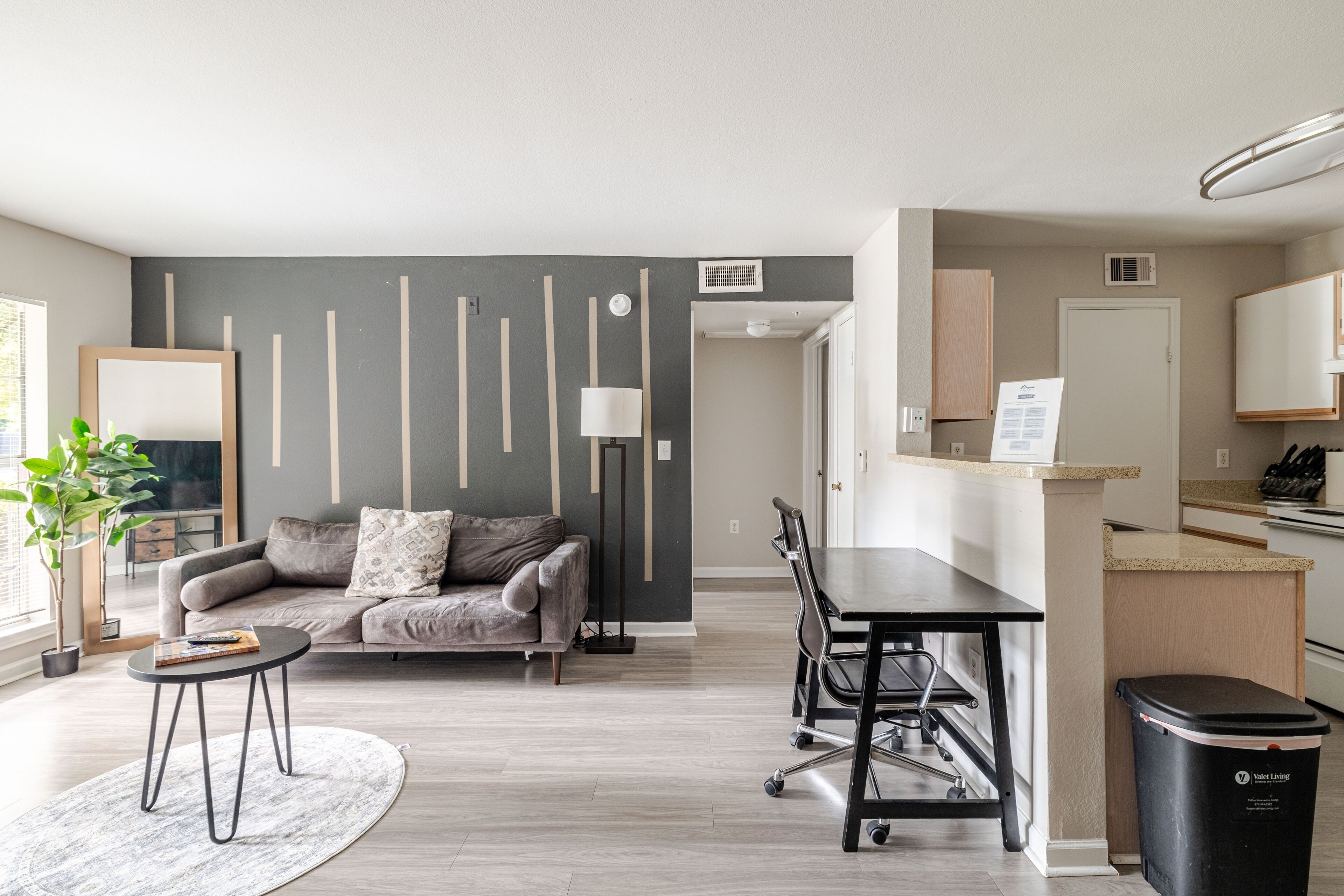 Een moderne woonkamer met een grijze bank, een salontafel en een eethoek met een tafel en stoelen.