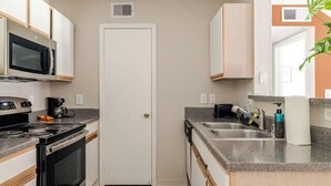 Cocina compacta con microondas, estufa y lavabo.