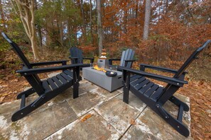 A stone patio with Adirondack chairs and a fire pit. - Wonderful 4-bedroom minutes from Trilith, QTS and U.S. Soccer Training Facility (Fayetteville)
