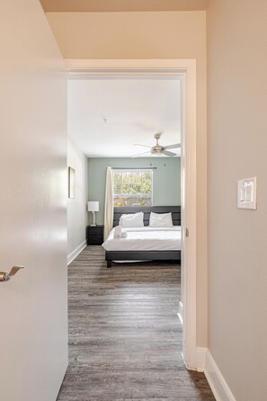 A bedroom with a bed, a ceiling fan, a window with curtains, and a view of greenery outside. - Green King 2Bed 2Bath| walk to NRG| 1mi Med Center (Houston)