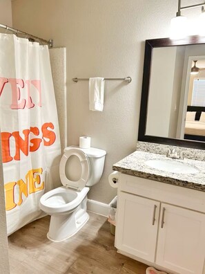 A bathroom with a toilet, a shower curtain with text, a towel rack, a sink, and a mirror. - Comfy King 2Bed 2Bath /Walk to NRG/ 1mi Med Center (Houston)