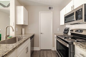 A compact kitchen with white cabinetry, a stainless steel sink, a microwave, and a stove. - Green King 2Bed 2Bath| walk to NRG| 1mi Med Center (Houston)