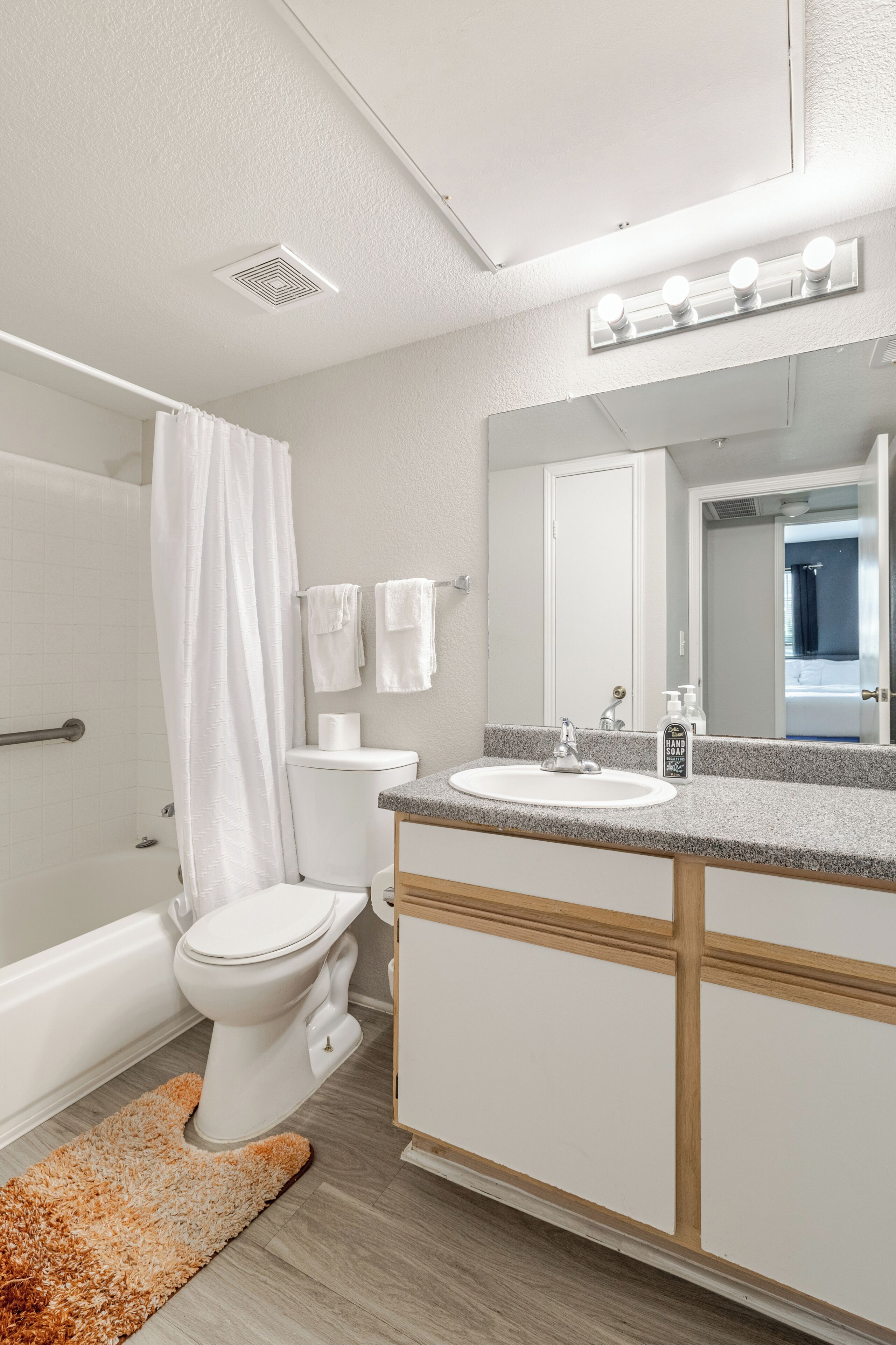 Een badkamer met een wit toilet, een wastafel, een spiegel en een douchegordijn.