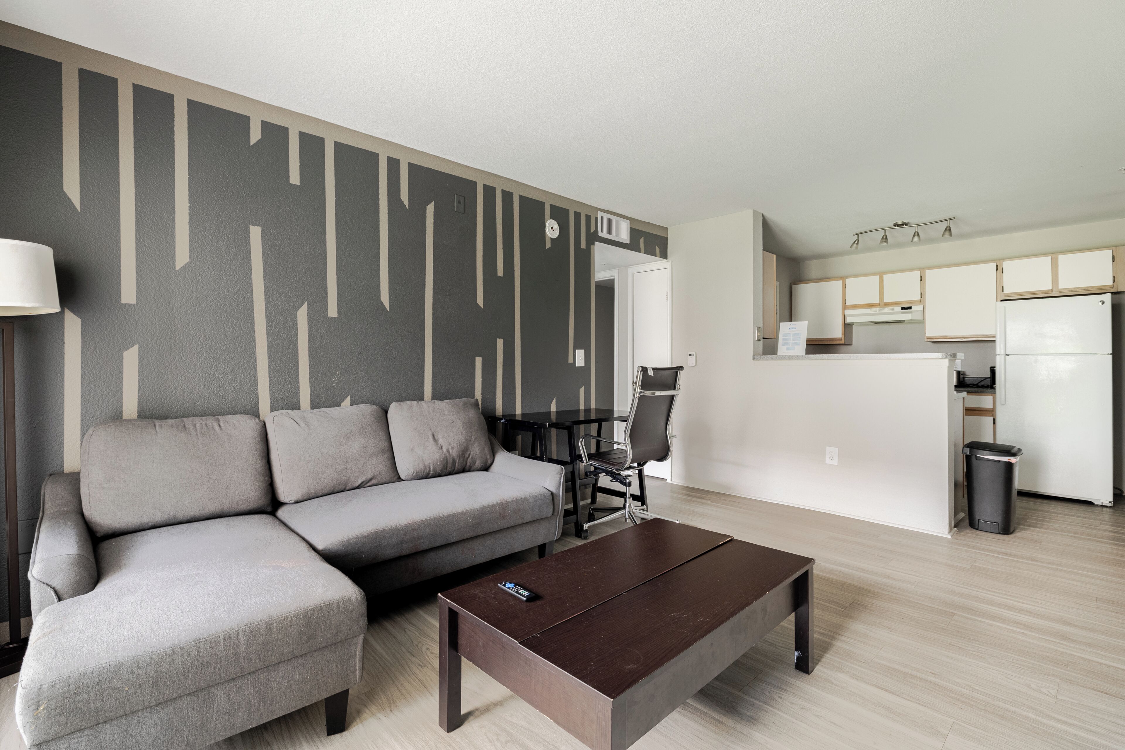 A modern living room with a sofa, coffee table, and a dining area with chairs.