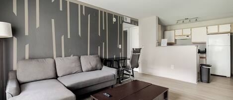 A modern living room with a sofa, coffee table, and a dining area with chairs.