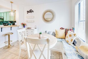 A modern kitchen with a dining area, a round table, and a sofa with patterned cushions.