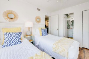 Un dormitorio con dos camas, un espejo y una puerta que da a un baño.