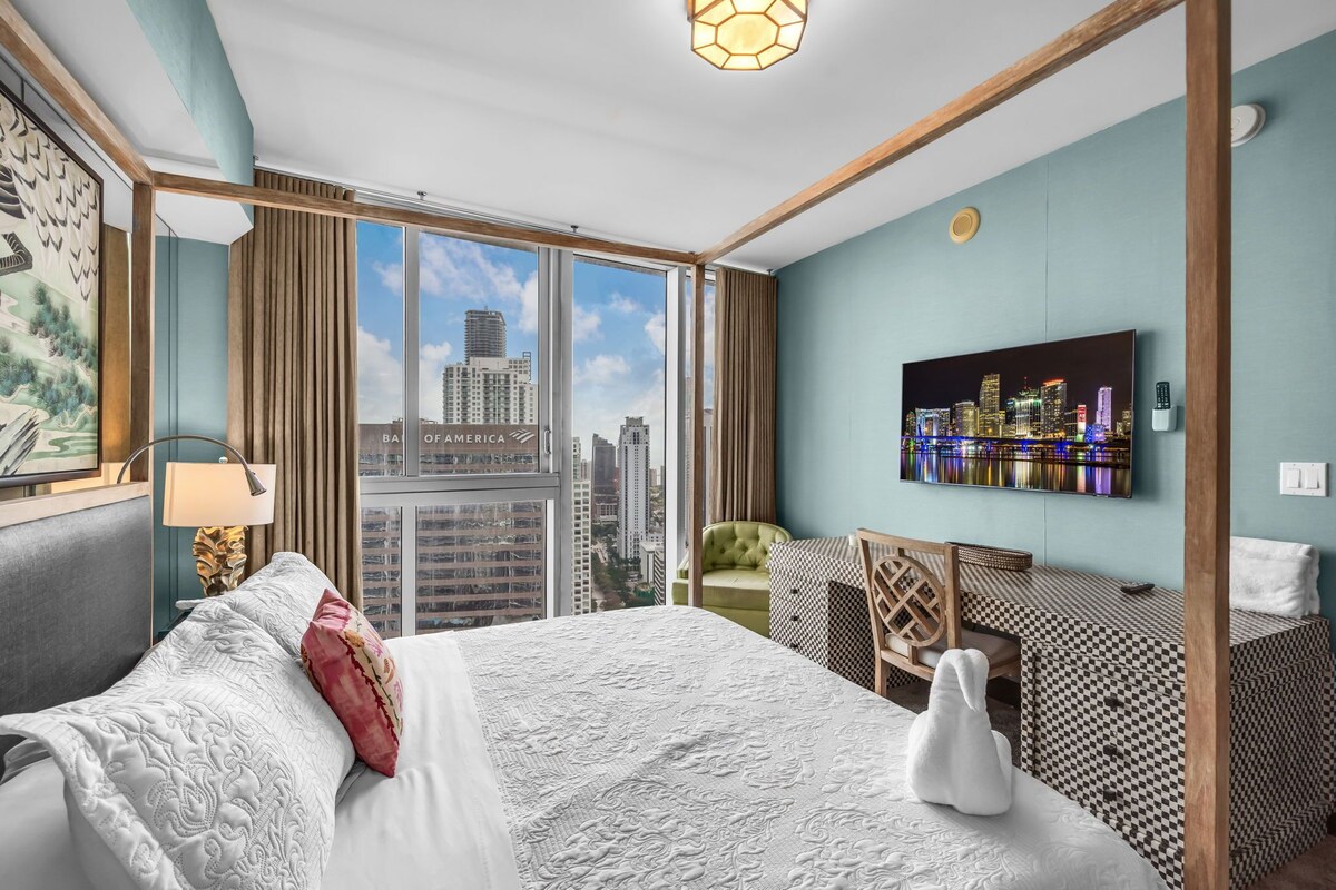 Une chambre d’hôtel avec un grand lit, un bureau, une chaise, une télévision et une vue sur la ville.