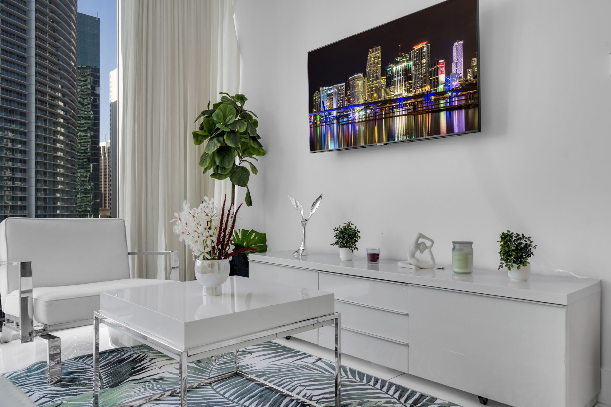 A modern living room with a white sofa, a glass coffee table, a white console table with decorative items, and a cityscape painting on the wall.