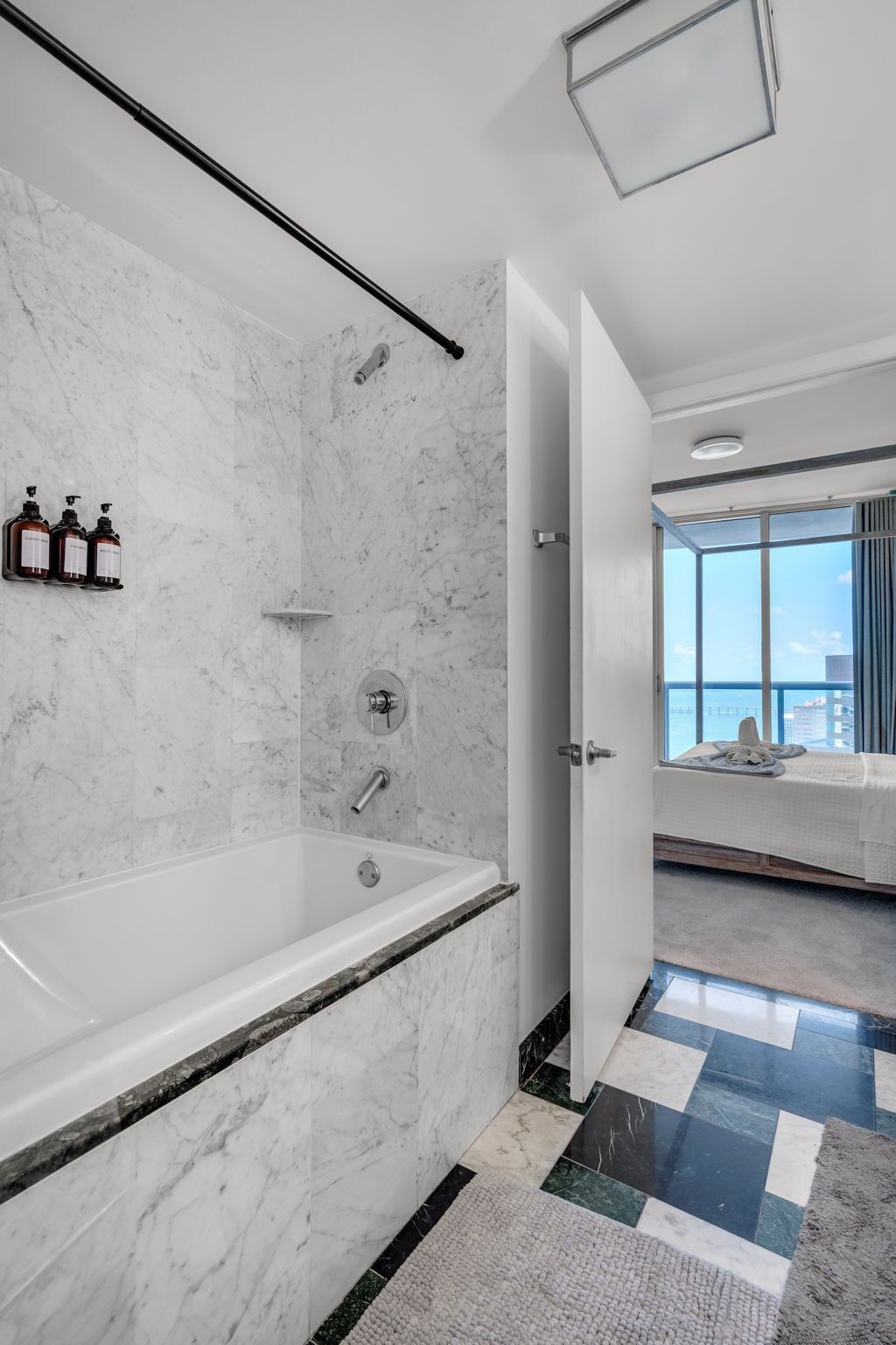 Un baño moderno con una bañera grande, paredes de mármol y vistas a la ciudad.