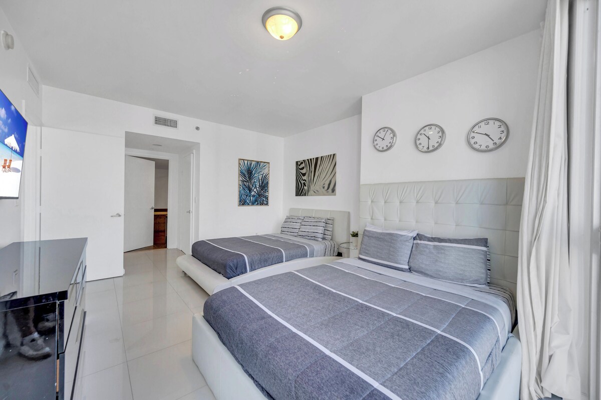 Une chambre moderne avec deux lits, un téléviseur à écran plat et un luminaire au plafond.