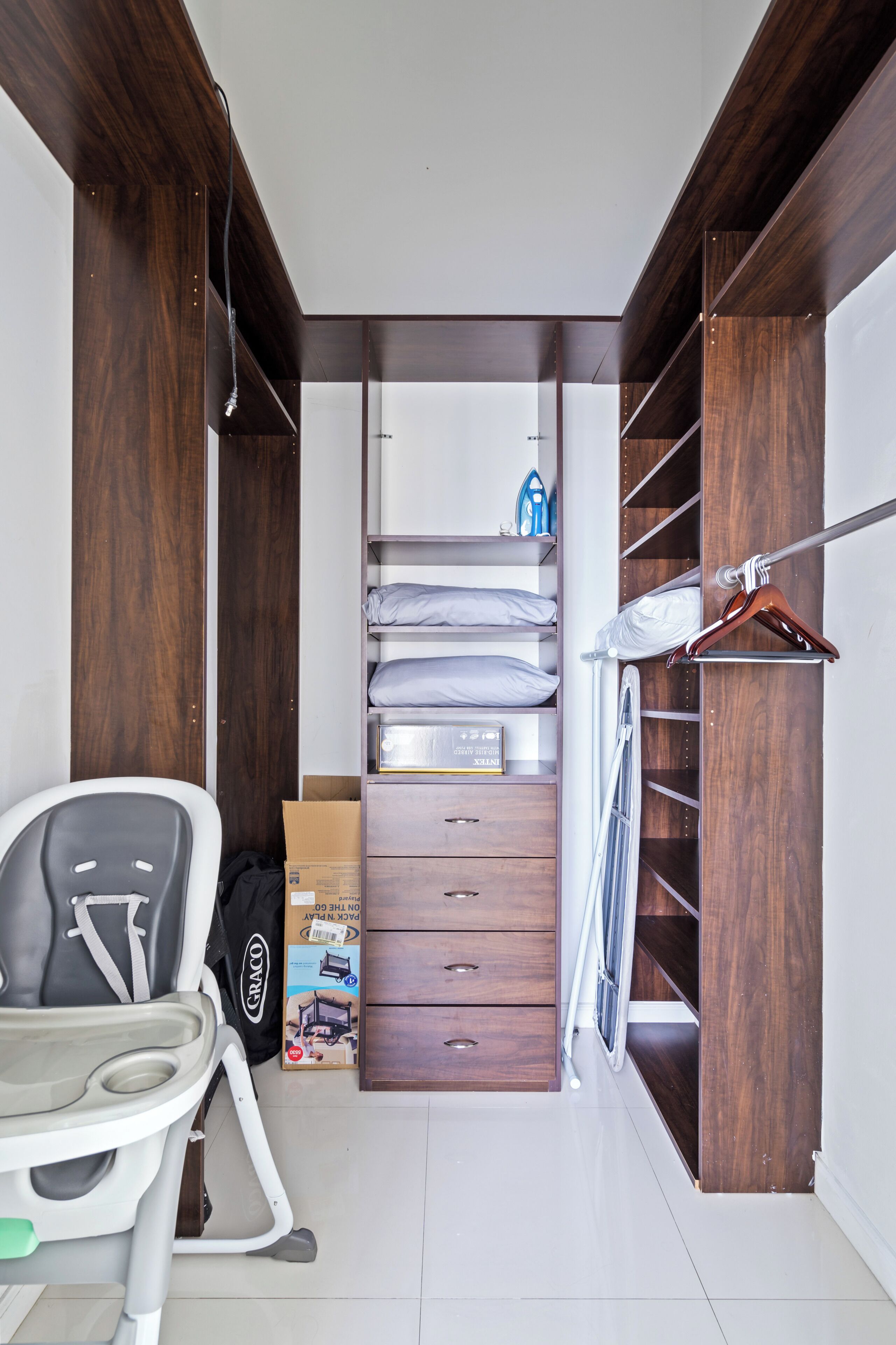 Een slaapkamer met een bed, nachtkastje, stoel, kledingkast en inloopkast.