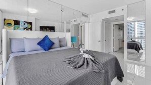 Una habitación de hotel moderna con una cama grande, un espejo y vistas a la ciudad.