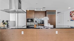 Una cocina moderna con campana de acero inoxidable, armarios de madera y horno empotrado.