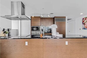 Una cocina moderna con campana de acero inoxidable, armarios de madera y horno empotrado.