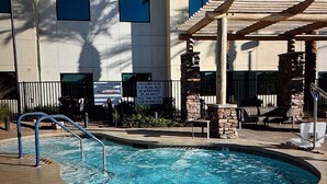 A swimming pool with a no diving sign, a covered seating area, and a building with multiple windows in the background.