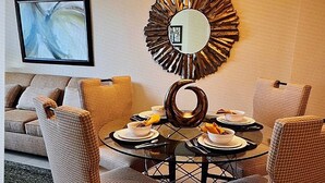 A dining area with a round table, chairs, and a decorative mirror on the wall.