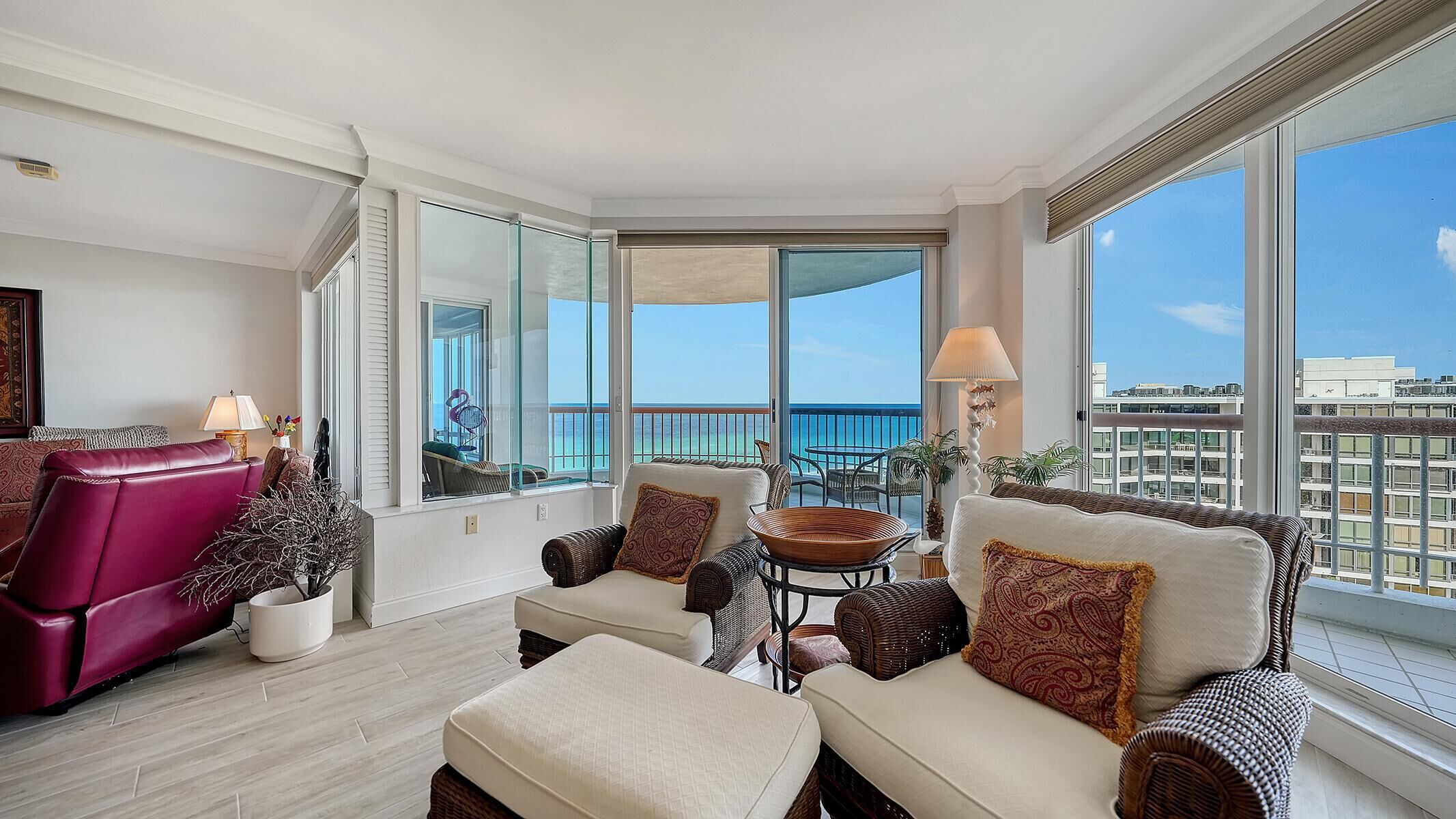 Corner living area with wicker armchairs, cream cushions, patterned pillows, and sliding glass doors to balcony.