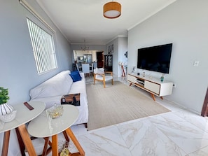 Una sala de estar moderna con sofá, televisión y comedor.