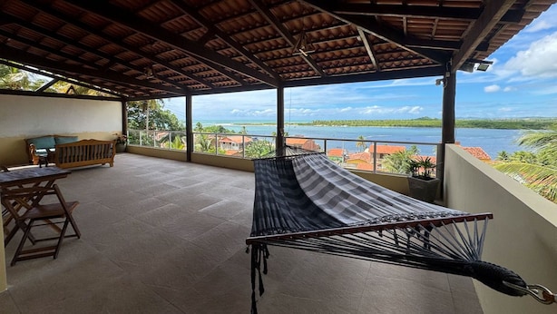 A covered outdoor area with a hammock, a wooden bench, and a table. - Casa com rea Gourmet Piscina e Vista do Mar (Canguaretama)