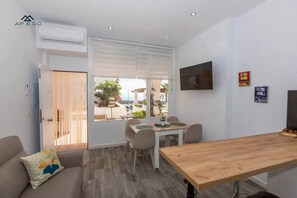 A modern interior with a dining area, a sofa, a TV, and a view of the outdoors. - Luxe Marina Premium Port views I (Almuñécar)