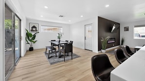 Uma sala de jantar moderna com uma mesa, cadeiras e um vaso de planta.