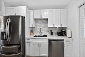 A modern kitchen with white cabinets, stainless steel appliances, and a marble backsplash. - Beautiful 3-bedroom house in peaceful Scottsdale perfect for relaxing stays (Scottsdale)