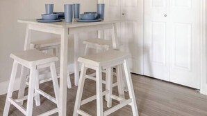 A dining area with a white table and four stools, a white door, and a light-colored floor. - Cozy 1BR with 2 Beds @5 min walk to NRG & near TMC (Houston)