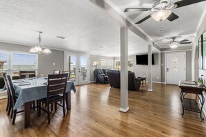 Un amplio espacio de sala con una mesa de comedor, asientos y ventiladores de techo.